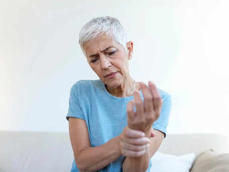 Older adult holding a painful wrist while seated