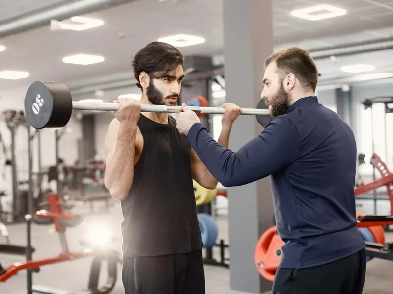 Trainer coaching a client through gym equipment work