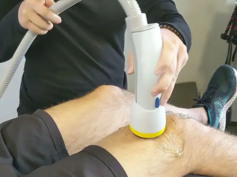 SoftWave applicator held against a client's knee